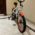 Vélo enfant neuf, vue de face du guidon et du garde-boue orange.