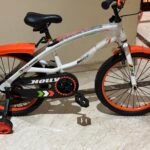 Vélo enfant blanc et orange, détail du cadre et du carter de chaîne.